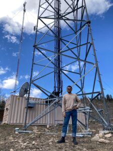 Will Floyd, broadcast engineer, stands in front of broadcast towers
